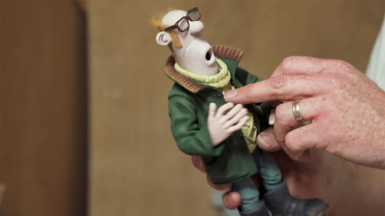 hands carrying a farmer puppet from 'Shaun the Sheep'